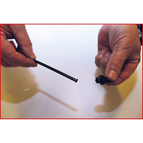 Zwei Hände halten einen schwarzen Stift und ein schwarzes Teil vor weißem Hintergrund.